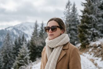 Femme portant des lunettes de soleil tendance en hiver sur un chemin enneigé en montagne