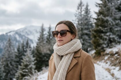 Femme portant des lunettes de soleil tendance en hiver sur un chemin enneigé en montagne