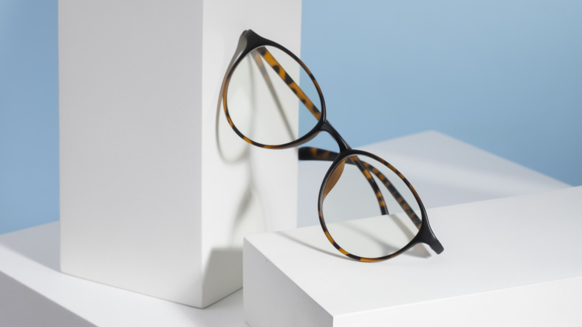 Une paire de lunette posée à la verticale sur un bloc blanc